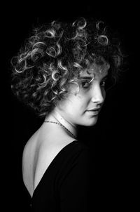 Close-up portrait of a serious young woman over black background