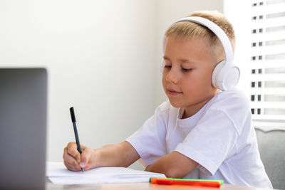 Portrait of boy drawing on book at home