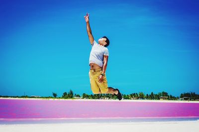 Man jumping over pink sea against sky