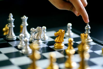 Close-up of person touching chess piece on board