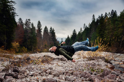 Man levitating over rocks land against sky