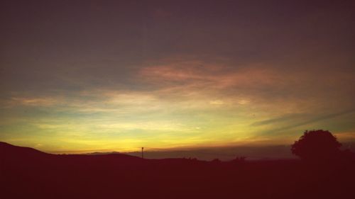 Silhouette landscape against dramatic sky during sunset