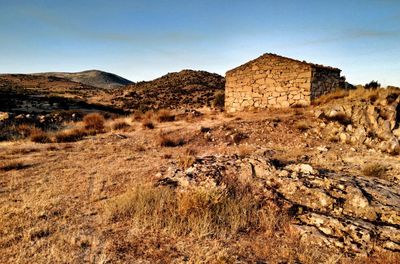 Stone wall on field against sky