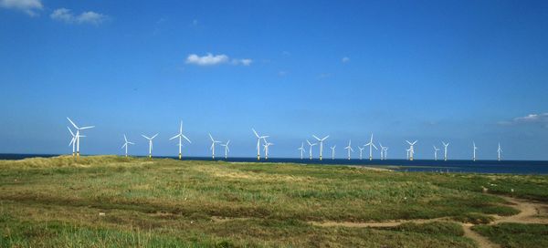 Wind turbines on field against sky