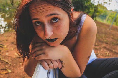 Close-up portrait young woman sitting on bench in park