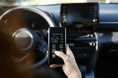 Businesswoman controlling smart house through mobile phone in car