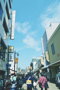 People on street amidst buildings in city against sky