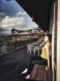 Side view of woman sitting on railing in city