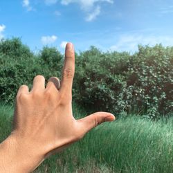 Cropped image of hand gesturing against trees