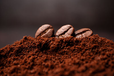 Closeup of three coffee beans at the mixed heap of roasted coffee with copy space