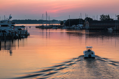 Sailboats moored at harbor against sky during sunset