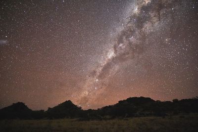 Silhouette landscape against star field at night