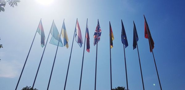 Low angle view of flags against clear sky during sunny day