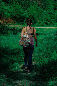 Rear view of backpack woman walking on grassy field