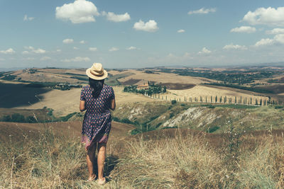 Rear view of woman standing on hill against sky