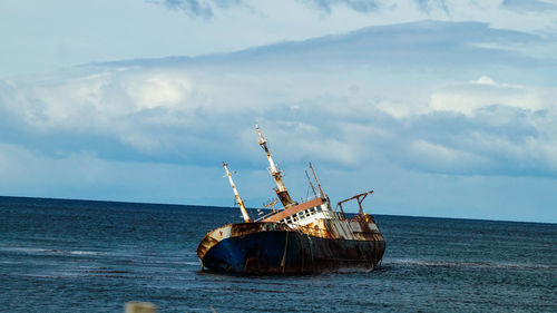 Abandoned boat in sea against sky