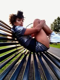 Full length portrait of woman sitting on bench at park