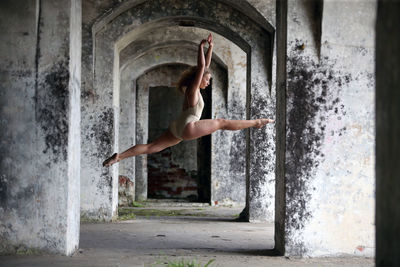 Full length of woman dancing in corridor of abandoned building