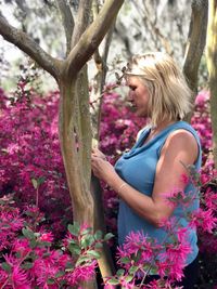 Woman with pink flowers on tree trunk