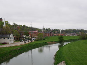 Scenic view of river by houses in town against sky