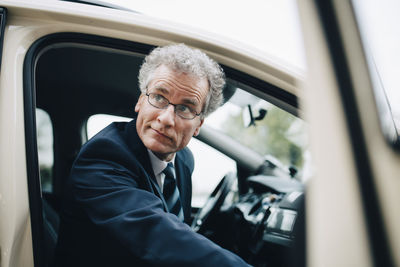 Mature male entrepreneur getting out of taxi during business trip in city