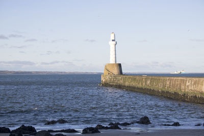 Lighthouse by sea against sky