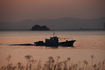 Silhouette boat in sea against sky during sunset