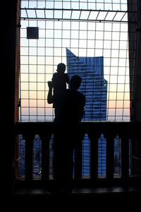 Silhouette men on window against sky