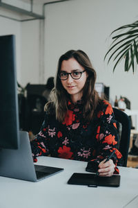 Young woman using phone while sitting on table