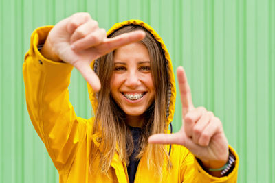 Portrait of young woman standing against wall