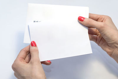 Close-up of woman hand holding red over white background