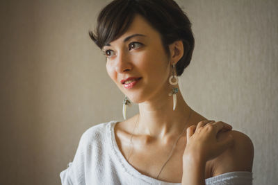 Portrait of a smiling young woman against wall