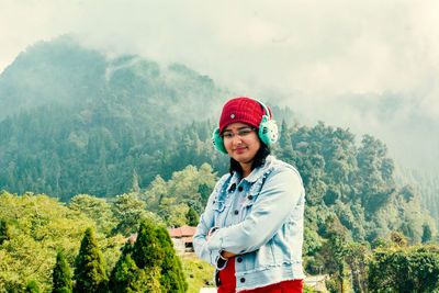 Portrait of young woman standing against trees