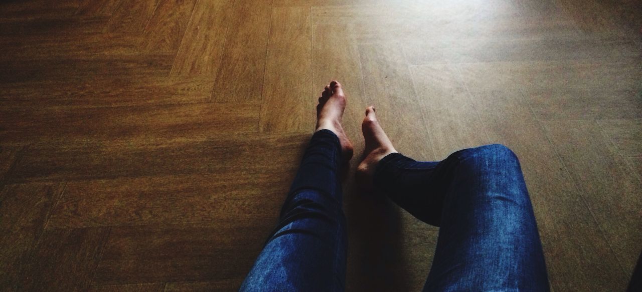 lifestyles, low section, person, personal perspective, leisure activity, relaxation, indoors, casual clothing, sitting, standing, legs crossed at ankle, human foot, barefoot, jeans, young adult, sunlight