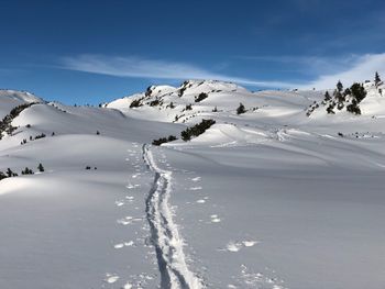 Scenic view of snow covered mountains against blue sky