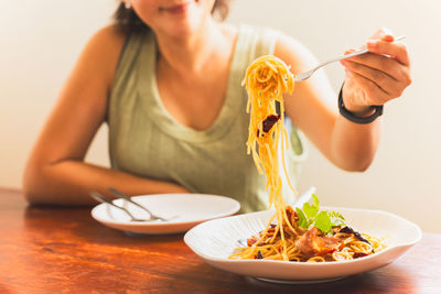 Woman eating spaghetti with friend in restaurant.