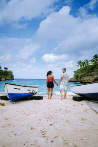 Rear view of women on beach against sky