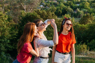 Smiling young woman wearing sunglasses against plants