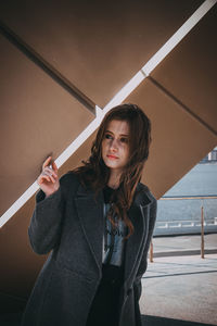 Portrait of smiling young woman standing against railing