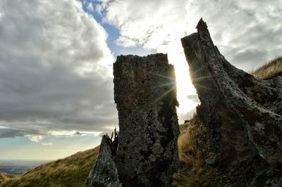 Low angle view of rock formation against cloudy sky