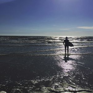 Silhouette man standing on beach against sky