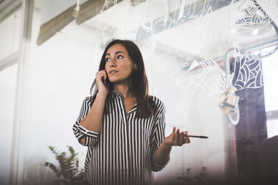 Young woman looking away while standing on mobile phone