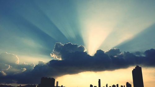 Low angle view of sunlight streaming through storm clouds