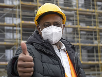 Indian construction worker wearing an ffp2 mask on construction site showing thumbs up gesture