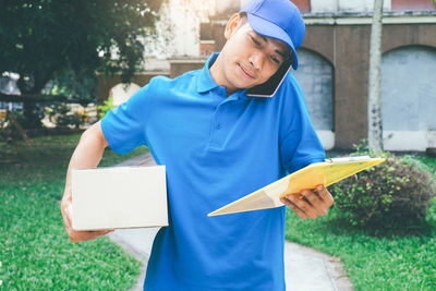 Delivery man with package talking on mobile phone