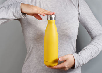 Midsection of man holding bottle against white background