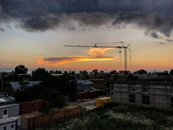 Silhouette trees and cityscape against sky during sunset