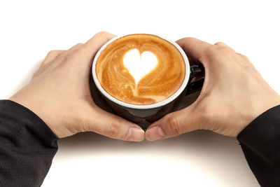 Close-up of hand holding coffee cup against white background