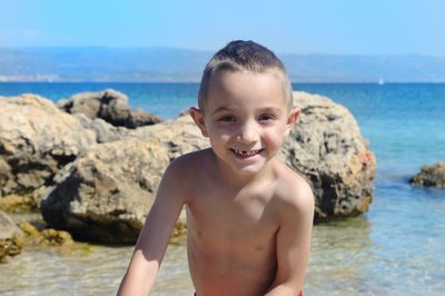 Portrait of happy boy on rock at sea shore