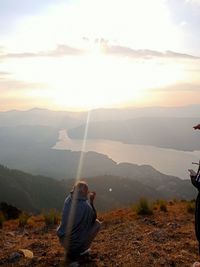 Rear view of man on landscape against sky during sunset